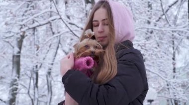 Portre sevimli genç kız a yorkshire korkunç sarılma bir kukuleta ile kaplı uzun saçlı ellerde bir kış karla kaplı Park genç köpek ve a evde beslenen hayvan yürüyüşe açık havada tutan yün kazak giymiş