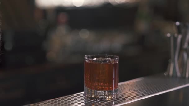 Sklenice whisky nebo jiného alkoholického nápoje s ledem stojí na panelu čítačů. Detailní záběr. — Stock video