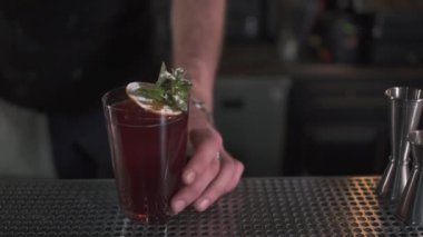 Taze kokteyl nane ile dekore edilmiş ve bar counter duran turuncu yakın çekim. Modern barda yapılan kokteyl. Alkol içki müşteri için hazır. Barmen içinde belgili tanımlık geçmiş bulanık figürü