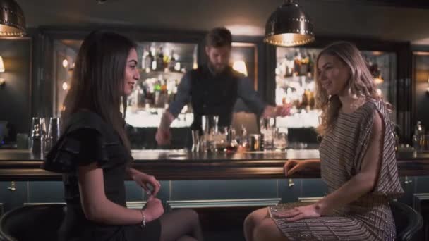 Barista che serve cocktail a belle ragazze mentre sono in chat e sorridente al moderno buon bar — Video Stock