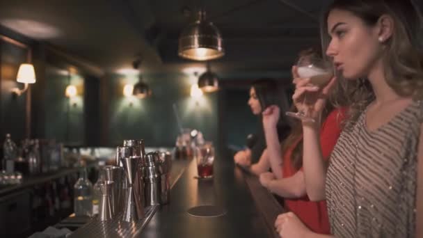 Три расстроенные и злые девушки сидят у бара и пьют коктейли один за другим, пытаясь забыть и напиться. — стоковое видео