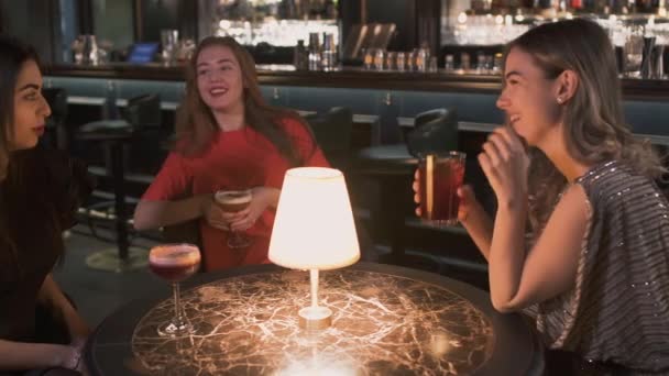 Üç mutlu kadın yakın bar içinde küçük masada oturuyor. Kızlar kutlama birlikte, sohbet ve gülümseyen zorundalar. Yalnız bayanlar eğlenin