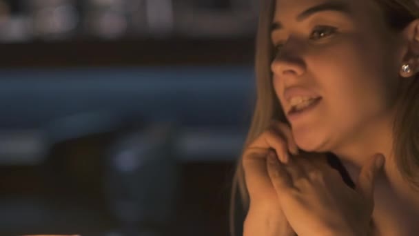 Retrato de una joven linda chica con hermosos ojos hablando de algo con amigos en un lugar acogedor y atmosférico. De cerca. — Vídeo de stock