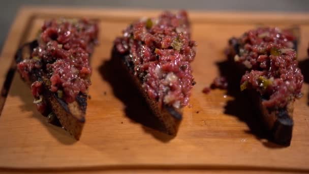 Smörgåsar av grillat mörkt bröd med kött som tjänstgör på träskiva i restaurangen. Närbild. — Stockvideo