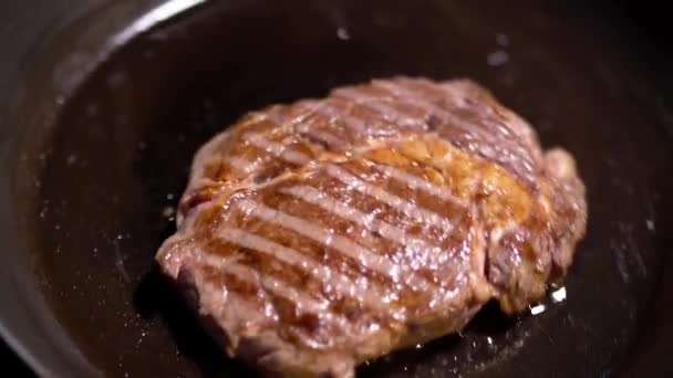 Juicy pedazo de carne a la parrilla freír en la sartén de cerca. La sartén está temblando. — Vídeos de Stock