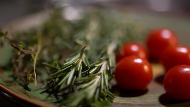 Čerstvý rozmarýn a chutné šťavnaté červená rajčata leží na kuchyňské desce closeup. Kamera se pohybuje zleva doprava. — Stock video