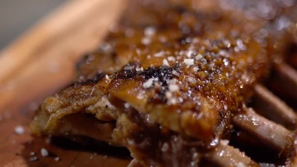 Costelas fritas suculentas e suculentas são polvilhadas com sal. Lindamente servindo na mesa de madeira. Fechar — Vídeo de Stock