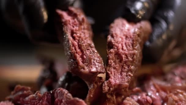 Close-up van handen in zwarte rubberen handschoenen houden gehakte stukken gestoofde vlees — Stockvideo