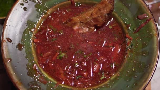 Piece of meat falls in the plate with borsch sprinkling the contents — Stock Video