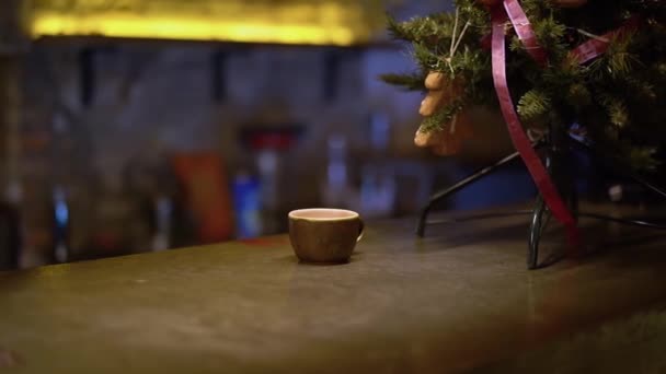 Pequeña taza y pequeño árbol de Navidad de pie en el mostrador de bar de cerca — Vídeo de stock