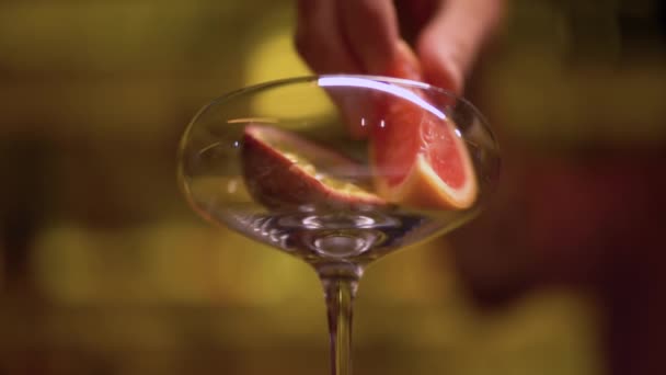 Männliche Hand legt Früchte aus nächster Nähe ins Glas. Barkeeper macht Cocktail — Stockvideo