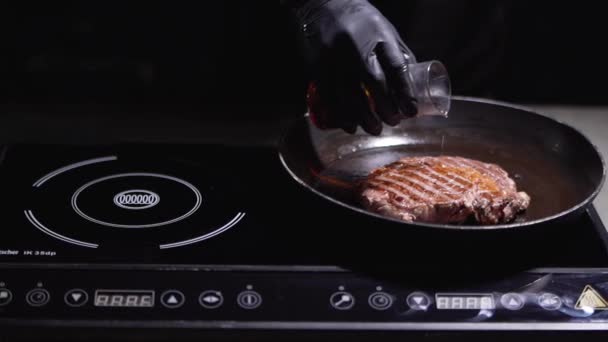 Nerozpoznaný cook nalévá alkohol na velký steak na pánvi zblízka — Stock video