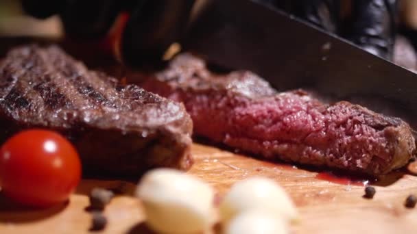 大きなナイフを持つ手は肉を切るステーキをクローズ アップ 黒手袋は食品を調理します レストランでの食事の準備 — ストック動画