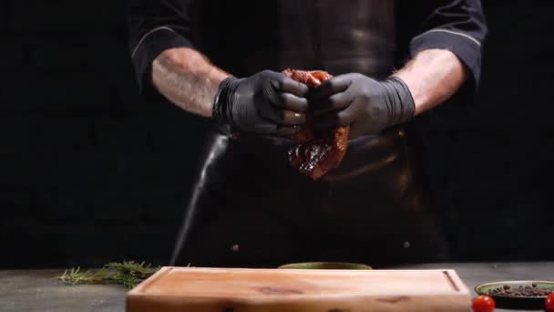 Les mains en gants de caoutchouc noir déchirent un gros morceau de viande de près. Jus dégoulinant sur planche à découper. Mouvement lent . — Video