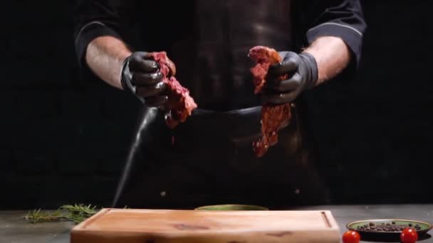 Las manos en guantes de goma negro arrojan dos trozos de carne en la tabla de cortar de cerca. En cámara lenta. De cerca. . — Vídeos de Stock