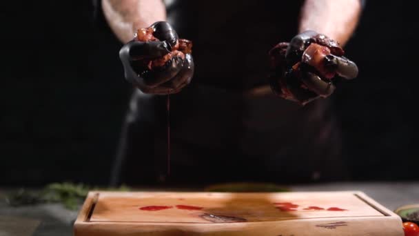 Hands in black rubber gloves squeeze two pieces of meat close up. Juice dripping on cutting board.. — Stock Video