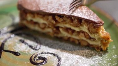 Bir tabağa yalan lezzetli pasta bir parça Close-up. Bir çatal fındık ile lezzetli kek tart bir parça keser. Ağır çekim.