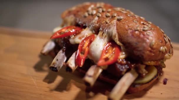 Lekker broodje met ribben liggen op de snijplank close-up. Koken voedsel met speciale recept in restaurant. Camera beweegt van rechts naar links. — Stockvideo