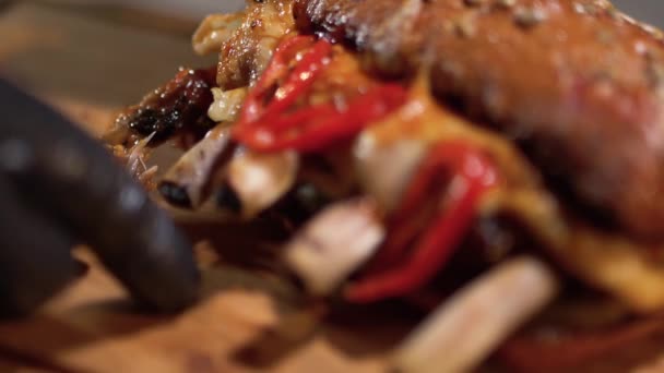 Рука в чорній їжі рукавички відриває ребро від великого бутерброда крупним планом — стокове відео