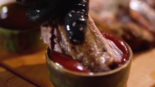 Appendere in guanto cibo nero mette costola succosa nella salsa di pomodoro da vicino — Video Stock