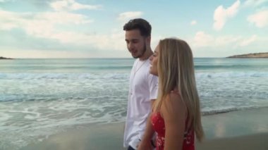 Birbirleriyle konuşma ve having fun boş sahilde günbatımı doğru yürüyüş elele aşık genç bir çift. Ağır çekim