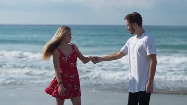 Lyckliga vackra paret på stranden nära fantastiska havet vågor dansar — Stockvideo