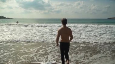 Dalgalar yarı çıplak sportif insan doğru açık havada güneşli günde pitoresk güzel deniz sahilde çalıştırıyor. Ağır çekim