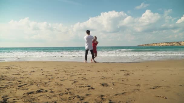 Joven hombre y mujer dando vueltas cogiéndose las manos en la playa. Lindos amantes felices juntos. Ocio en verano. Movimiento lento . — Vídeos de Stock