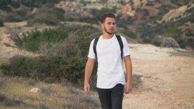 Genç adam sırt çantası Hills ile seyahat eden sakallı. Yalnız turist arıyorum far gözleri için elini koyar. Yakışıklı adamın etkin boş