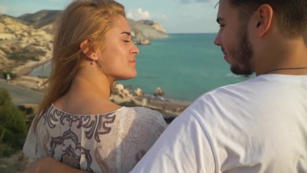 Hombre y mujer hablar sentado en el banco, hermoso paisaje marino está en el fondo. Pareja feliz pasar tiempo juntos al aire libre. Ocio en verano. Cámara se mueve alrededor — Vídeos de Stock