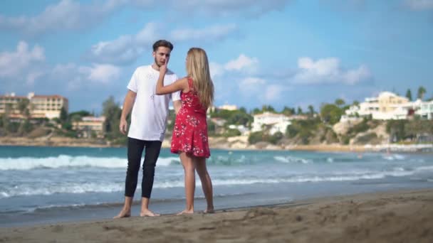 Pareja joven de pie en el mar rocoso costo de hablar emocionalmente, Hombre y mujer discutiendo, el hombre hace gestos agudos. Conflicto en la familia joven — Vídeo de stock