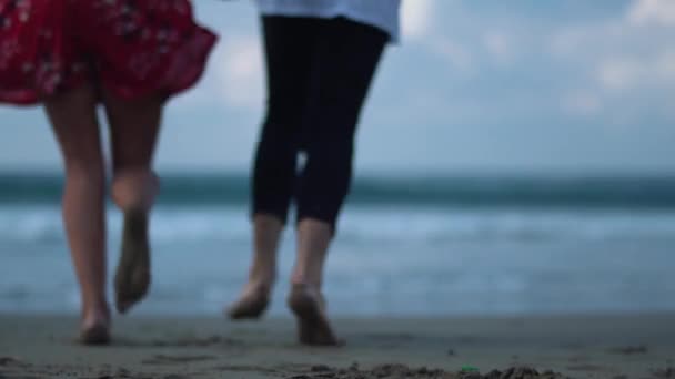 Lopend naar de golven jonge mooie paar buiten op het pittoreske prachtige zee strand op zonnige dag — Stockvideo