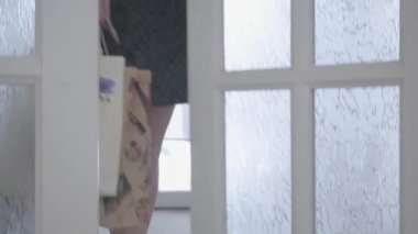 Neşeli genç şık kadın moda elbise ve beyaz spor ayakkabı alışveriş torbaları ile ev girer ve bir kredi kartı gülümseyen ve sevindirici elinde tutar. Alışveriş kavramı