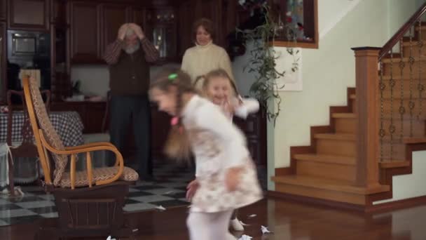 Szemtelen gyermekek dobott dolgok körül a házat, a nagyszüleim. Nagymama és nagypapa állva fejét kezével háttér — Stock videók