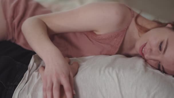 Vacker kvinna i rosa natt klänning liggande på bröstet av sin pojkvän, hålla handen och röra vid hans kropp varsamt närbild. Älskande par vila hemma tillsammans. Fritid för unga familj. — Stockvideo