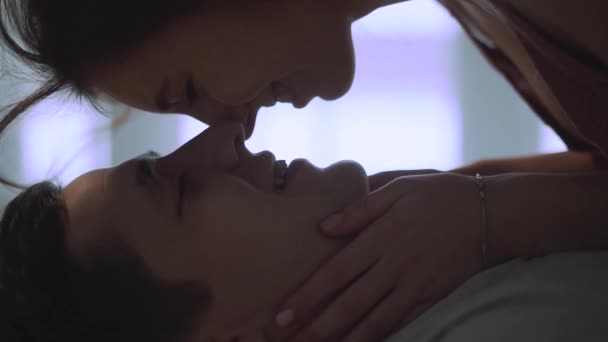 Chica frotando narices con su novio, luego besándose. Una pareja de enamorados descansan juntos en casa. Ocio de la familia joven — Vídeo de stock