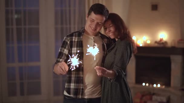 Fiatal férfi és a nő áll a modern nappali csillagszórók tartja kezében. Boldog pár időt együtt otthon, ők mosolyogva. Szabadidő, a fiatal család — Stock videók