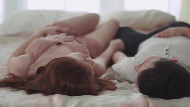 朝背中の快適なベッドに横たわって話幸せなカップルをクローズ アップ。男と女が手を繋いでいます。恋人幸せ一緒に。若い家族のレジャー。若いカップルの入札関係. — ストック動画