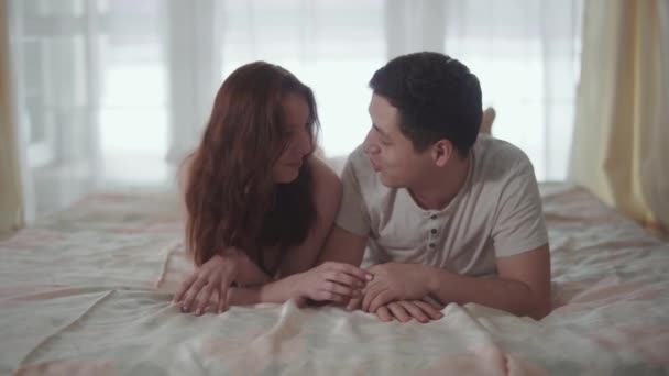 Närbild av lyckliga paret prata ligger i bekväma sängen på morgonen. Man och kvinna som håller händer. Älskare lycklig tillsammans. Fritid för unga familj. Anbud förhållandet av ett ungt par. — Stockvideo