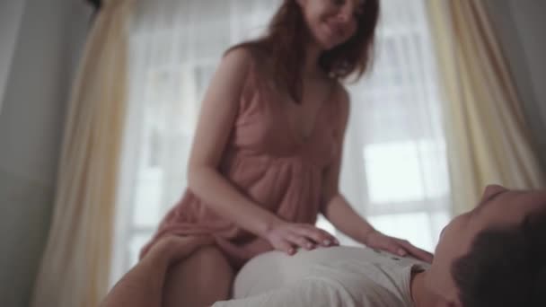 A young kissing couple lying on a white soft carpet on the floor. Young lovers. Leisure of young family. Tender relationship of a young man and girl. — Stock Video