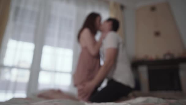 Young lovers kissing on the background, standing on their knees, image is blurred. Man throws black panties of girl to camera. Happy couple have foreplay — Stock Video