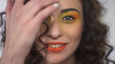 Bir curl kaldırma kadar parlak yapmak kıvırcık güzel kızla genç gülümseyen portresi kapatın. Ağır çekim.