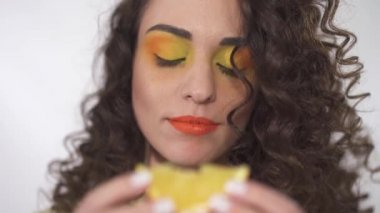 Sevimli genç kıvırcık kız portre kadar sulu turuncu bir dilim ısırma kadar parlak yapmak ile yakın