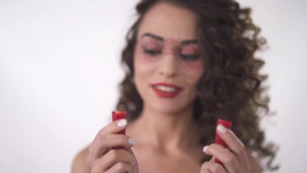 Porträt eines lächelnden, lustigen, lockigen Mädchens, das zwei Hälften roter Chilischoten betrachtet. rückt der Fokus vom Vordergrund in den Hintergrund. Zeitlupe — Stockvideo
