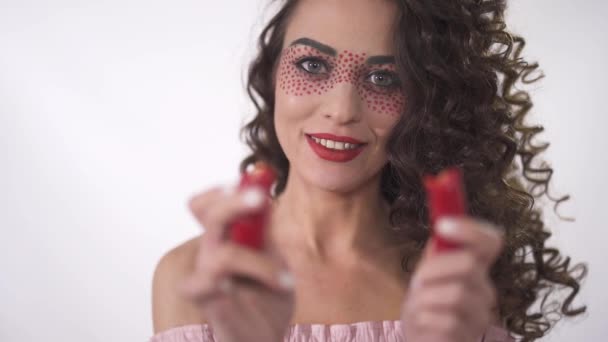 Portrait de sourire drôle jeune fille bouclée regardant deux moitiés de piments rouges. Mouvement lent — Video
