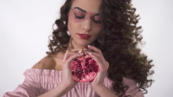 Portrait of pretty girl squeezing pomegranate, smiling and looking in camera with beautiful eyes. Slow motion — Stock Video