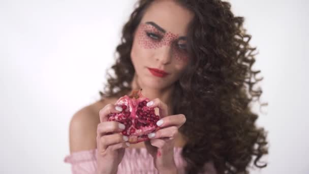 Retrato sorrindo engraçado jovem garota encaracolado espremendo e quebrando em partes romã madura suculenta. Movimento lento — Vídeo de Stock