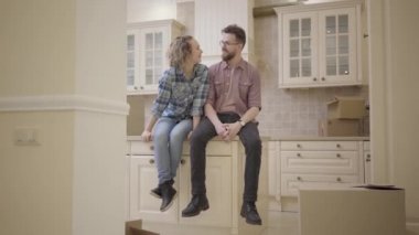 Sakallı yakışıklı ve tatlı kadın yeni dairede mutfak masasında oturuyordu. Aile planları yeni daire hakkında tartışın. Yeni bir ev içine evli çift hamle.
