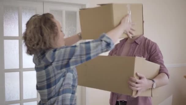 Et legende par med papkasser stående ved døren. Et ungt par flytter ind i et nyt hjem. Familie har en sjov flytning til nye lejligheder . – Stock-video