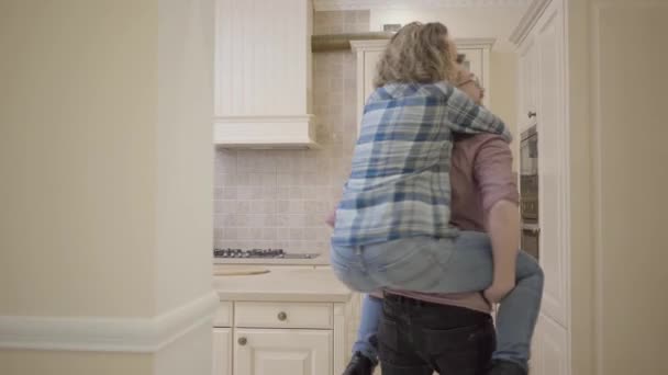 Bonne famille a déménagé dans leur nouvelle maison. Un mari joyeux porte une femme heureuse et souriante autour de son appartement. Concept de famille heureuse — Video